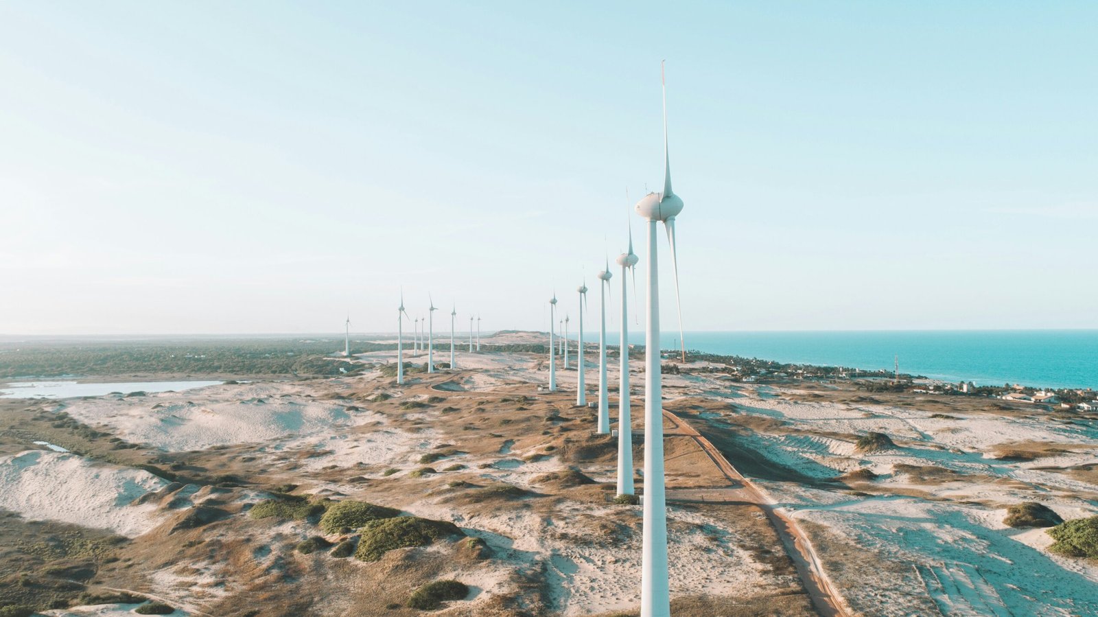 a row of wind turbines sitting on top of a sandy beach